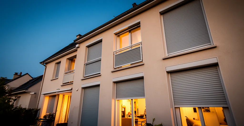 Vue extérieure d'une maison avec volets motorisés s'ouvrant et se fermant automatiquement au crépuscule